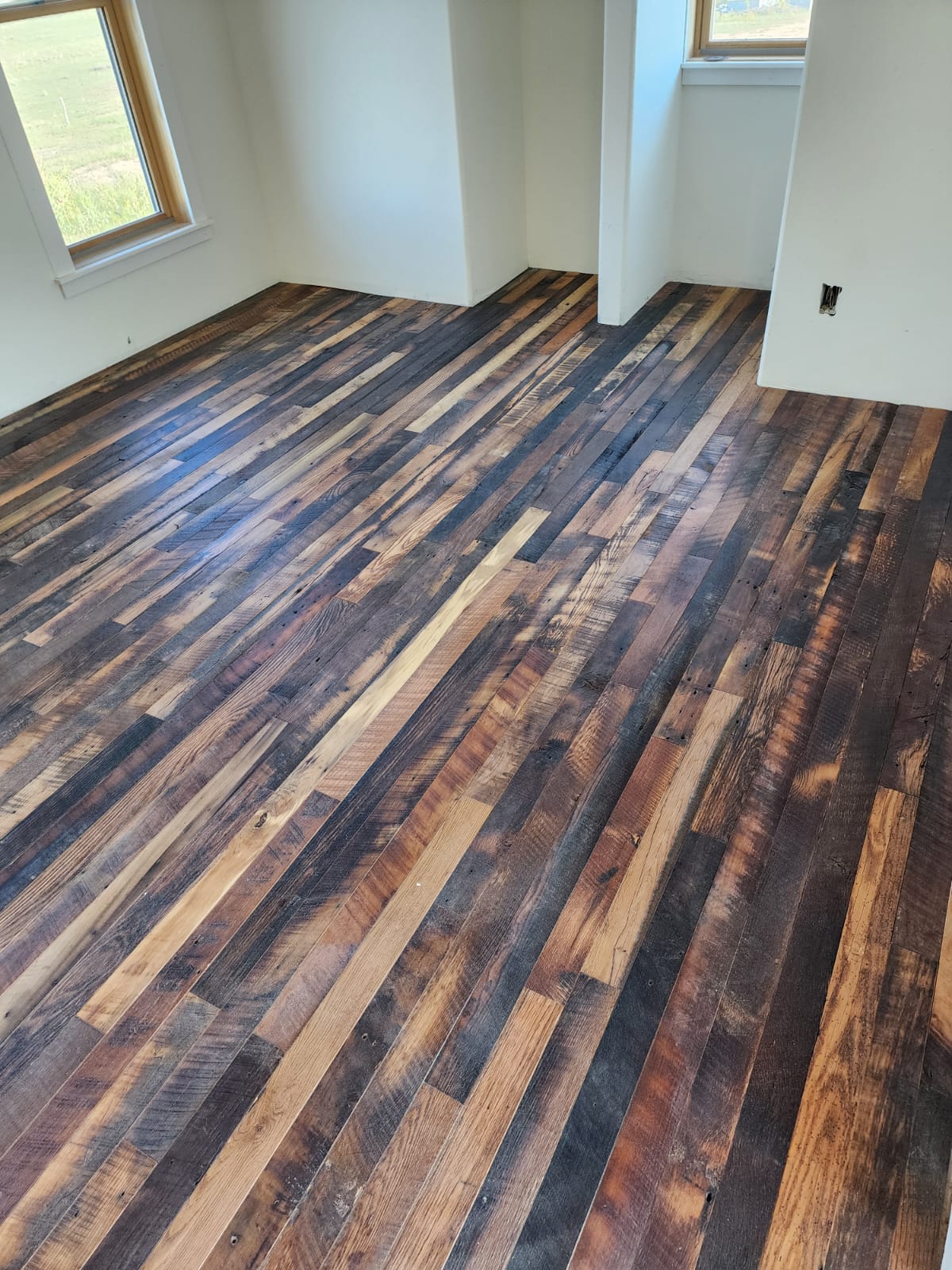 Reclaimed mixed-tone hardwood floor installed in a bright room by OnSite Flooring