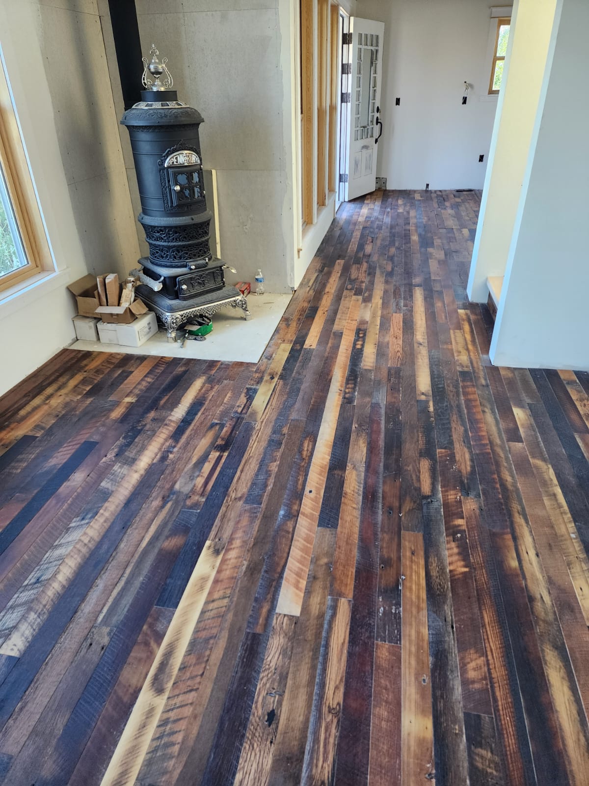 Reclaimed wood plank flooring running through a hallway and entry